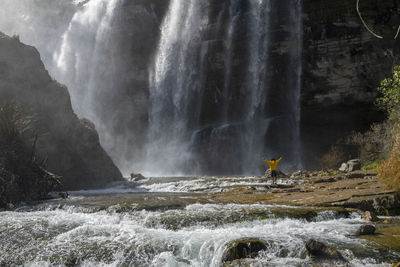 Man standing by waterfall outdoors