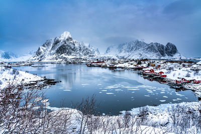 Frozen lake by snowcapped mountain against sky