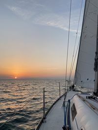 Sailboat sailing on sea against sky during sunset