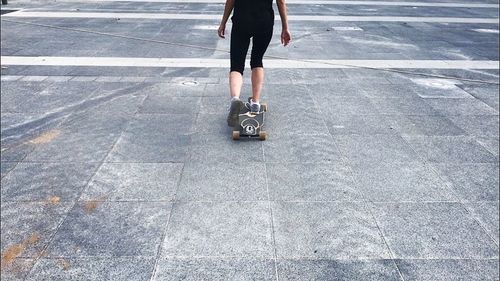 Low section of woman skateboarding on road