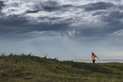 Rear view of man standing on field against sky