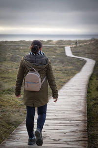 Vertical photo of a woman walking along a wooden walkway