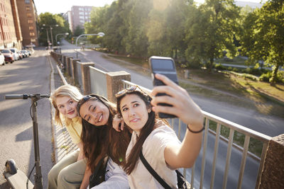 Young female friends spending time together outdoors and taking selfie