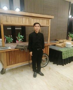 Portrait of young man standing by potted plant on table