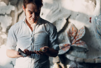 Artist holding hammer standing in workshop