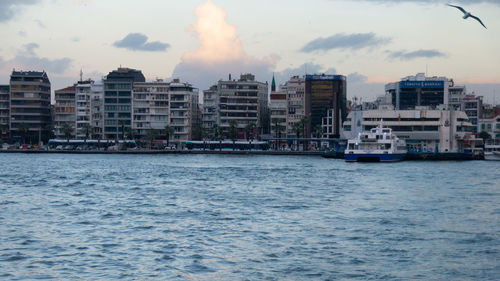 Sea by buildings against sky in city