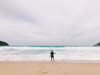 Rear view of woman on beach against sky