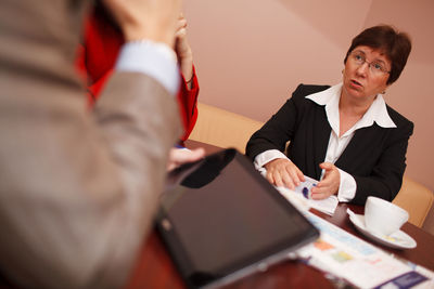 Smiling business colleagues discussing while sitting on table 