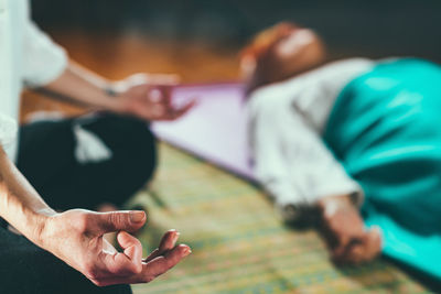 Close-up of mature woman relaxing while yoga instructor meditating at spa