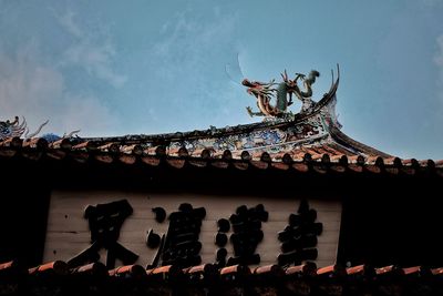 Low angle view of sculptures on roof of building against sky