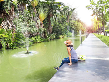 Rear view of woman in park by water