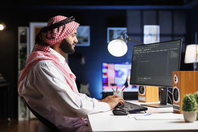 Rear view of man using laptop at office