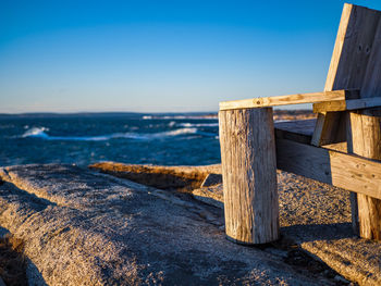 Wooden posts on beach against clear blue sky