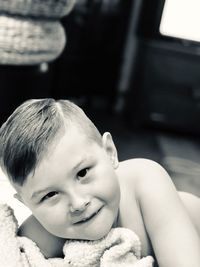 Portrait of cute smiling boy lying on bed at home 