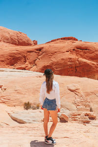 Rear view of woman standing on rock formations in desert