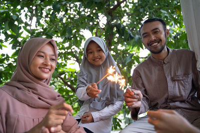 Portrait of smiling friends standing against trees