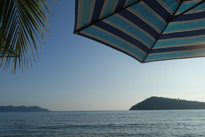 Beach umbrella by sea against sky