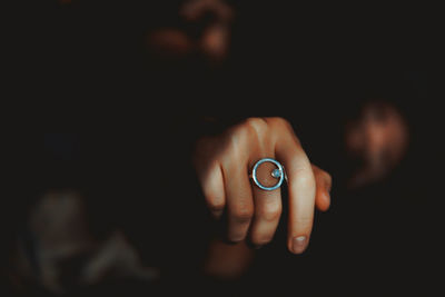 Cropped hand of woman wearing ring in darkroom