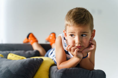 Portrait of boy sitting on sofa at home