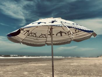 Close-up of parasol on beach against sky