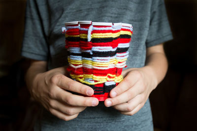 Midsection of woman holding multi colored cup with woolen artwork