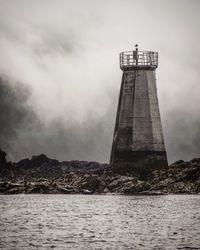 Lighthouse by sea against sky