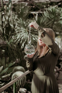 Woman holding jewelry against trees