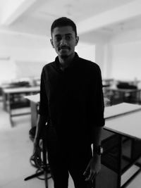 Portrait of young man standing against wall