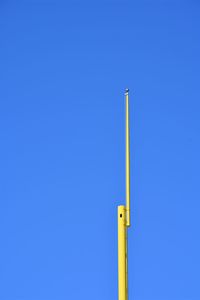 Low angle view of yellow pole against clear blue sky