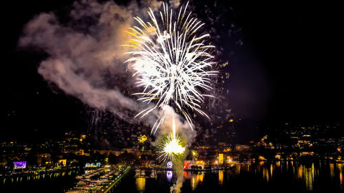 Firework display in city against sky at night