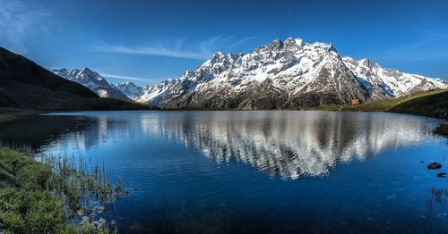 Scenic view of lake and snowcapped mountains against blue sky