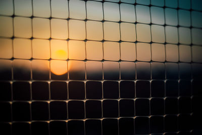 Full frame shot of metal grate against sky during sunset