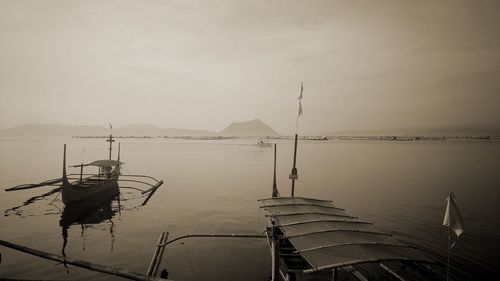 Sailboats moored in sea against sky