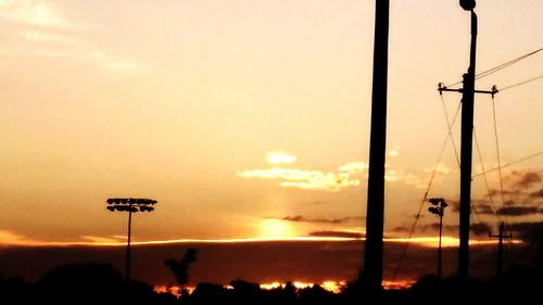 Low angle view of silhouette floodlight against sky during sunset