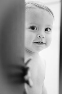 Portrait of cute shirtless baby peeking through ajar