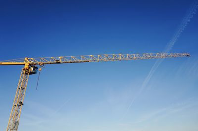 Low angle view of crane against blue sky