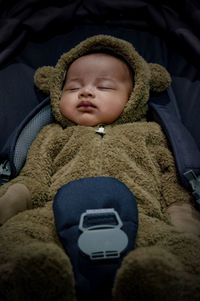 High angle view of toddler in bear suit sleeping in car