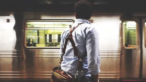 Rear view of man looking at train at subway station