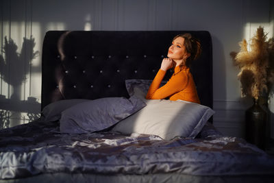 Girl on the bed in the rays of light