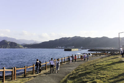 People on shore against sky