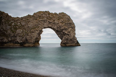 Rock formation in sea against sky