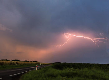 Lightning over landscape against sky at sunset