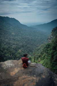 Rear view of man sitting on mountain