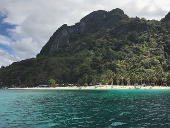 Scenic view of sea by mountains against sky