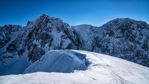 Scenic view of snowcapped mountains against clear blue sky