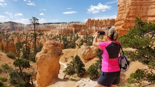 Rear view of woman photographing on rock