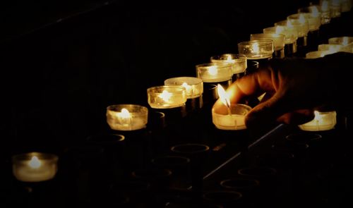 Cropped hand placing tea light on shelf in darkroom