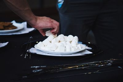 Close-up of man with marshmallows in plate on table