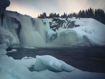 Scenic view of waterfall against sky during winter