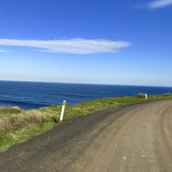 Road by sea against blue sky